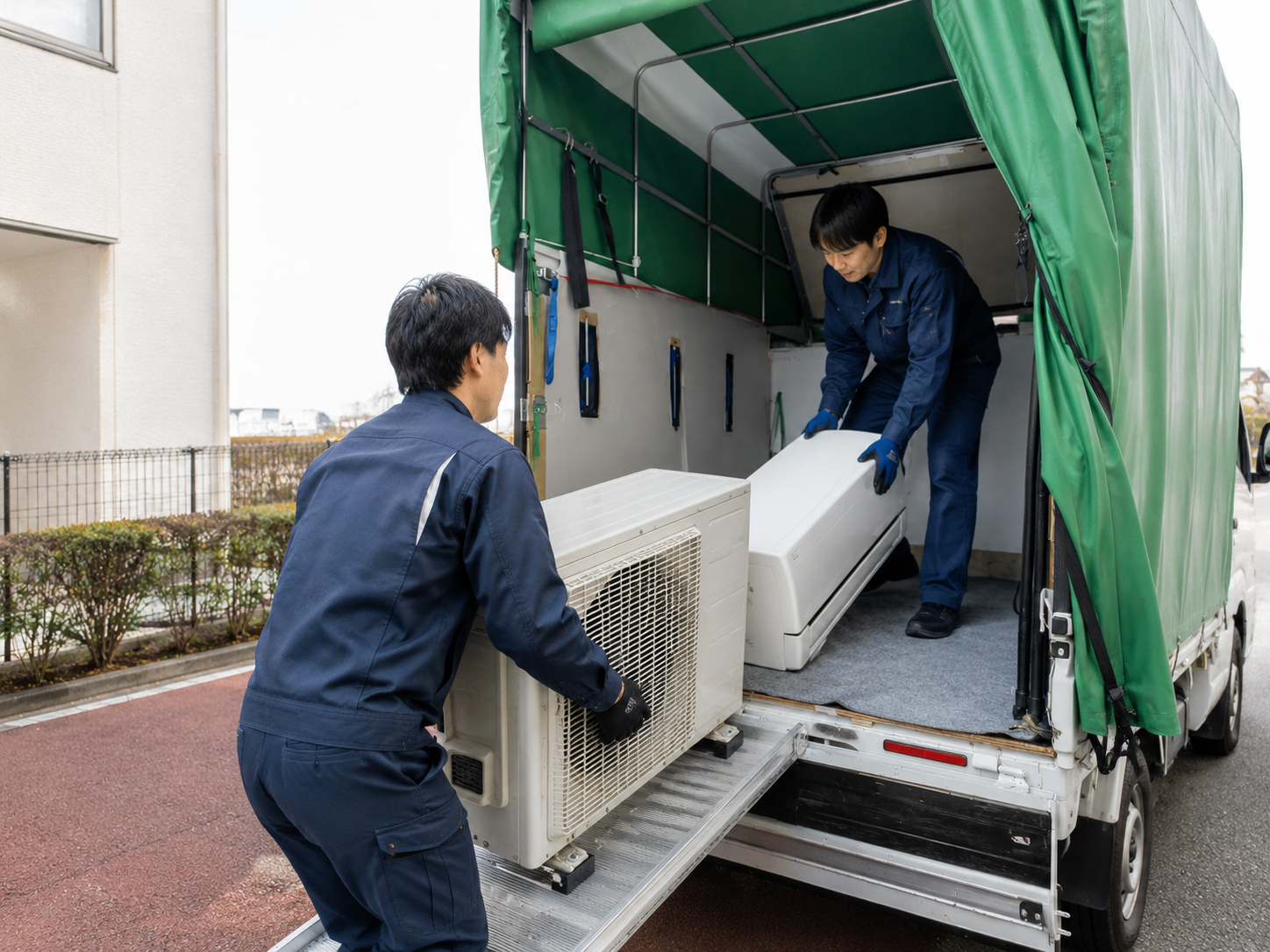 取り外したエアコンを車両へ積み込む作業風景